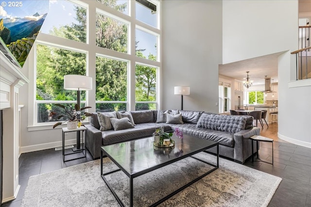 living area featuring an inviting chandelier, baseboards, and a high ceiling