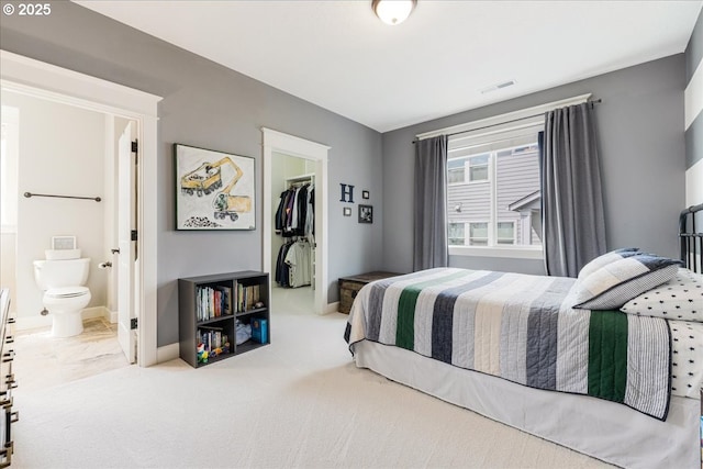 bedroom featuring a walk in closet, visible vents, baseboards, a closet, and connected bathroom