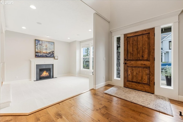 foyer with wood-type flooring, recessed lighting, baseboards, and a tiled fireplace