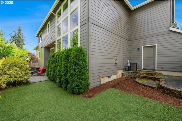view of side of property featuring central air condition unit, a yard, and a patio area
