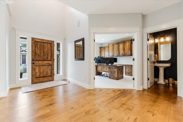 entryway with built in study area, baseboards, and light wood finished floors