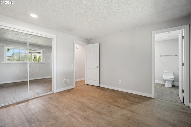 4702 NE 49th Ave, Vancouver, WA 98661 - unfurnished bedroom featuring a textured ceiling, wood finished floors, baseboards, a closet, and connected bathroom