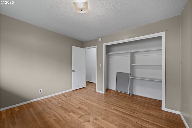 unfurnished bedroom featuring a textured ceiling, wood finished floors, a closet, and baseboards