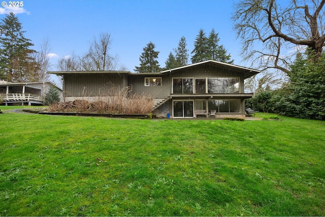 rear view of house featuring stairway and a lawn