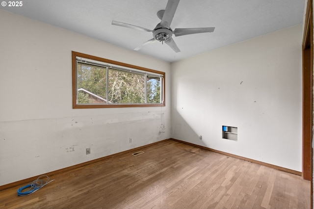 unfurnished room with ceiling fan, visible vents, baseboards, and wood finished floors