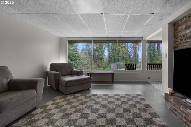 living area featuring a drop ceiling, plenty of natural light, and concrete floors