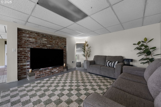 living area featuring a paneled ceiling and baseboards