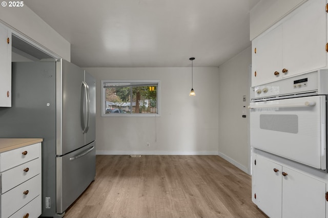 kitchen featuring light countertops, white cabinets, light wood finished floors, and oven