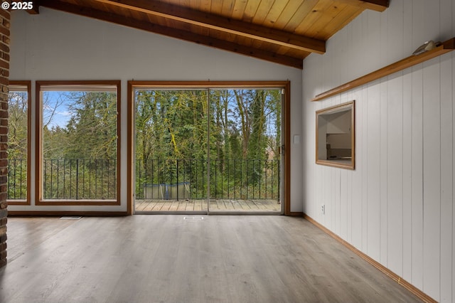 interior space featuring lofted ceiling with beams, wood ceiling, plenty of natural light, and wood finished floors