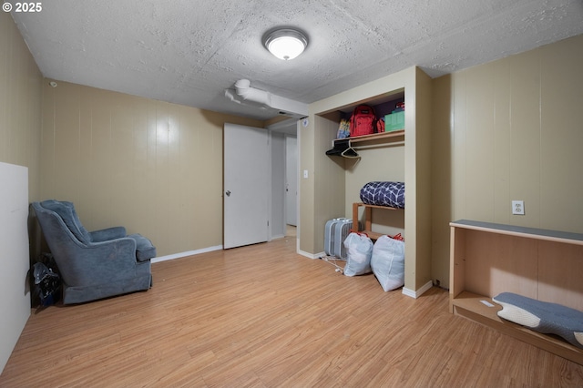 living area featuring light wood-style floors, baseboards, and a textured ceiling