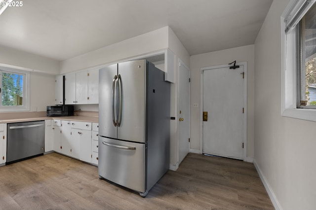 kitchen featuring light countertops, white cabinets, light wood finished floors, and stainless steel appliances