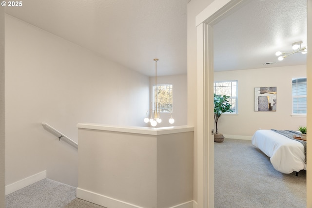 hall featuring a chandelier and light carpet