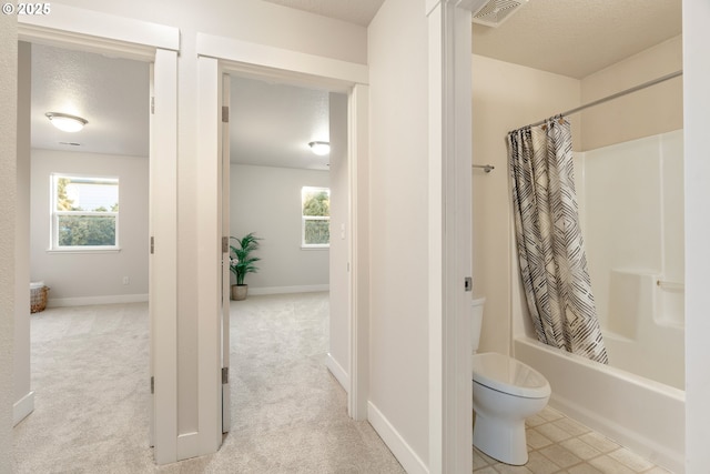 bathroom with shower / tub combo, toilet, and a textured ceiling