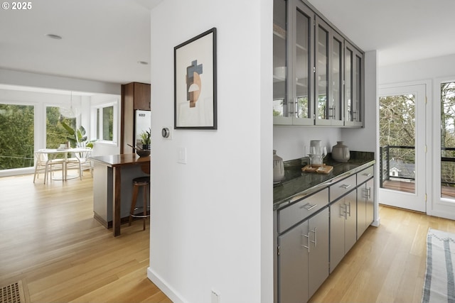 bar with light wood finished floors, stainless steel refrigerator, and a wealth of natural light