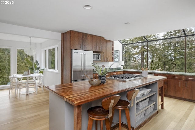 kitchen with stainless steel appliances, butcher block countertops, light wood-style flooring, and a center island