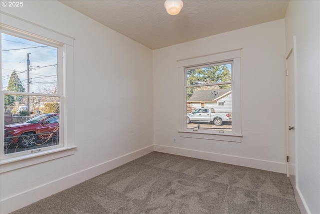 carpeted spare room featuring a textured ceiling and a healthy amount of sunlight