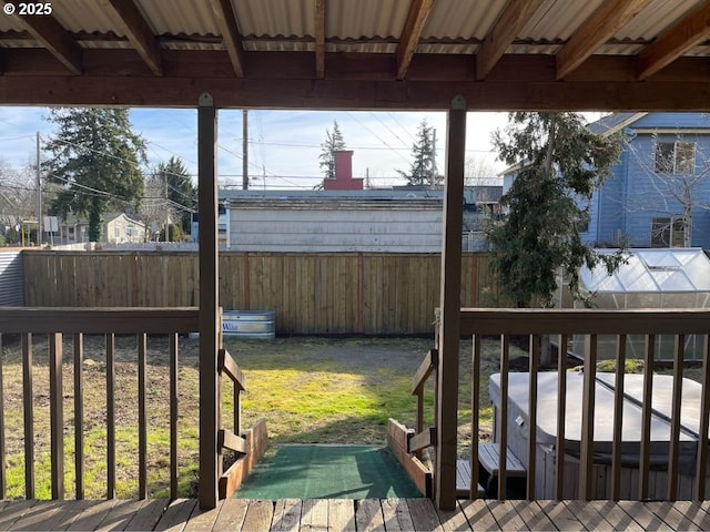 wooden deck featuring a lawn and a covered hot tub