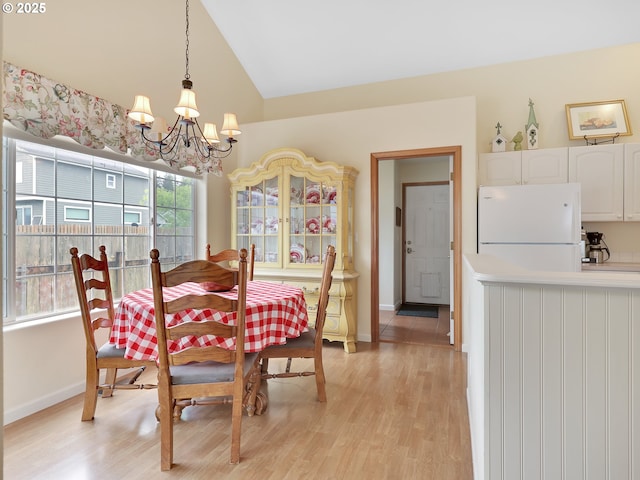 1689 Huckleberry Dr, Seaside, OR 97138 - dining space featuring a chandelier, vaulted ceiling, light wood-style floors, and baseboards