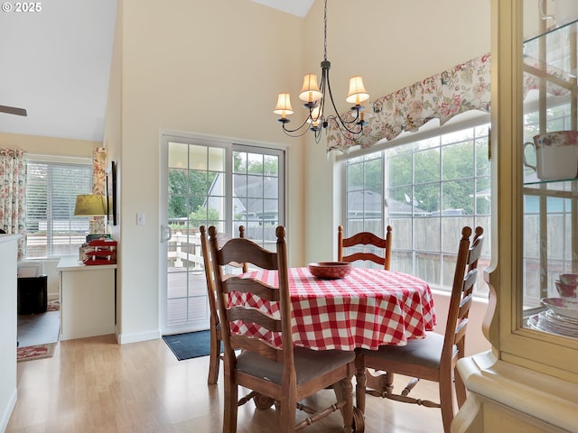1689 Huckleberry Dr, Seaside, OR 97138 - dining area featuring a chandelier, light wood-style floors, a high ceiling, and baseboards