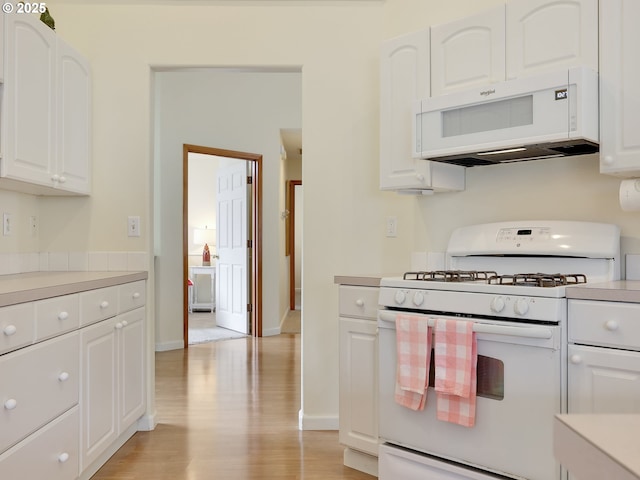 1689 Huckleberry Dr, Seaside, OR 97138 - kitchen featuring white appliances, light countertops, light wood-style flooring, and white cabinetry