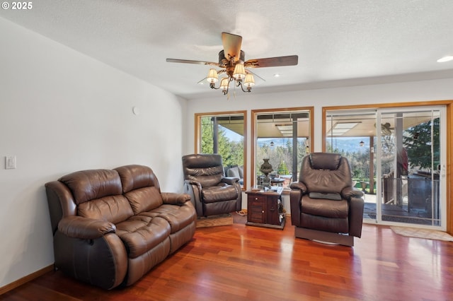 living room with hardwood / wood-style flooring, ceiling fan, and a textured ceiling