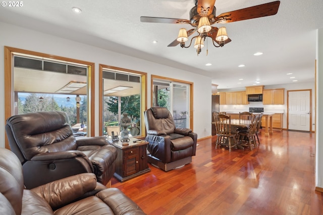 living room with ceiling fan, dark wood-type flooring, and a textured ceiling