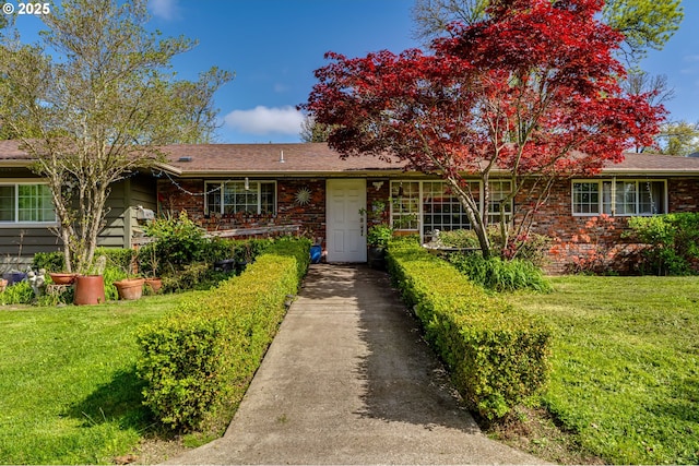 ranch-style home featuring a front lawn, brick siding, and driveway