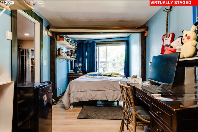 bedroom featuring wood finished floors and fridge