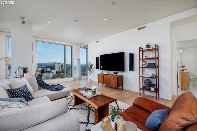 living room with a wall of windows and light hardwood / wood-style floors