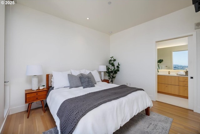 bedroom featuring connected bathroom and light wood-type flooring