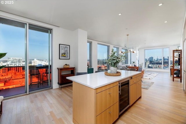 kitchen featuring light brown cabinets, light wood-type flooring, a kitchen island, a wall of windows, and beverage cooler