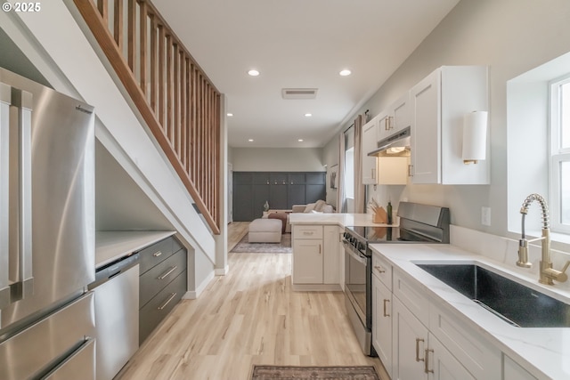 kitchen with open floor plan, appliances with stainless steel finishes, a sink, and white cabinets