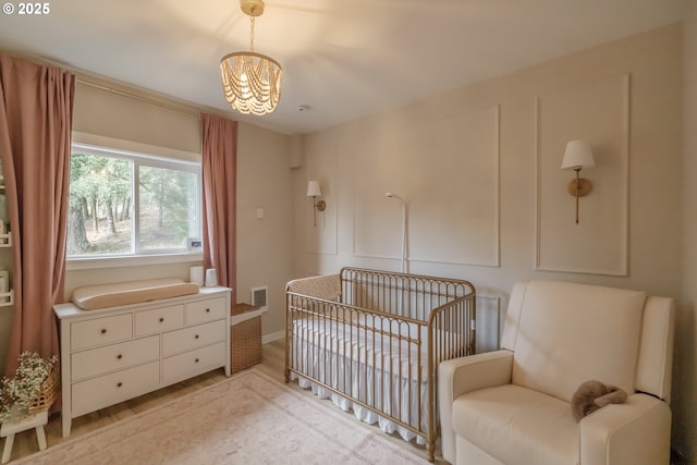 bedroom featuring light wood-style floors, visible vents, and a crib