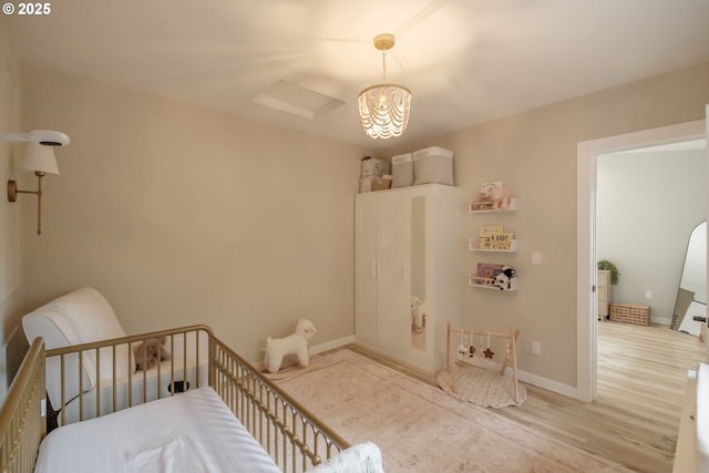 bedroom with light wood finished floors, attic access, and baseboards