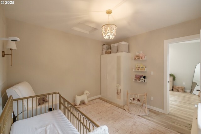 bedroom with a chandelier, wood finished floors, and baseboards