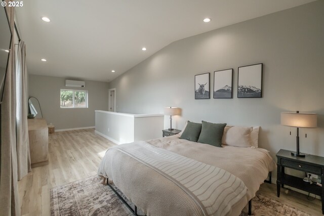 bedroom with vaulted ceiling, light wood finished floors, a wall mounted AC, and recessed lighting