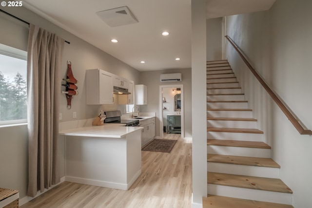 kitchen with white cabinets, stainless steel electric range, light countertops, under cabinet range hood, and a sink