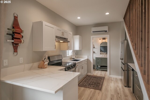 kitchen featuring electric range, a wall mounted AC, a sink, under cabinet range hood, and light wood-style flooring