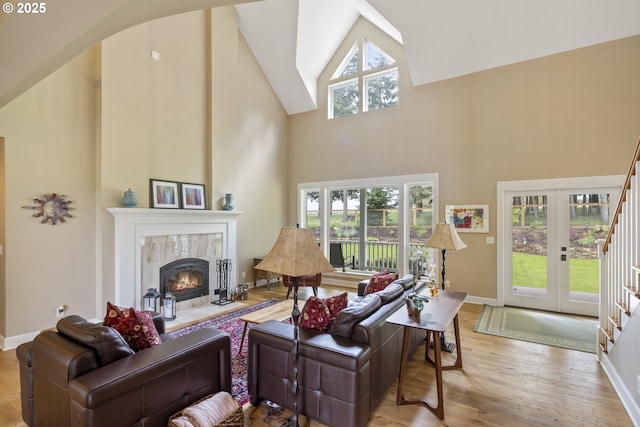 living area featuring high vaulted ceiling, wood finished floors, a tile fireplace, baseboards, and arched walkways