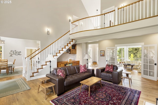 living room featuring a towering ceiling, stairs, wood finished floors, and baseboards