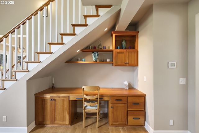 office area with built in desk, light wood finished floors, and baseboards