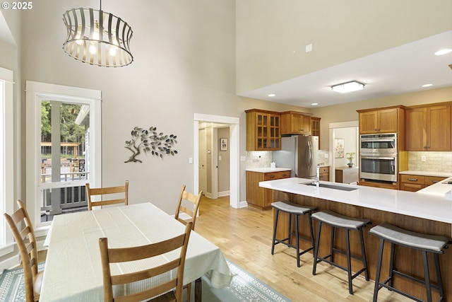 dining room featuring light wood finished floors, a towering ceiling, recessed lighting, and a chandelier