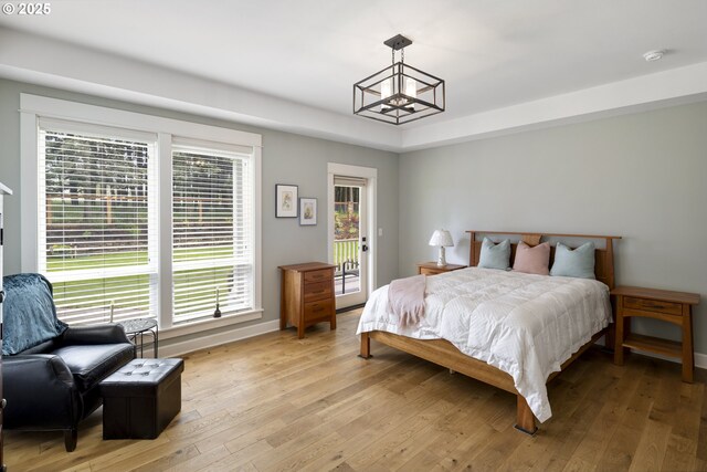 bedroom with a chandelier, access to outside, light wood-type flooring, and baseboards