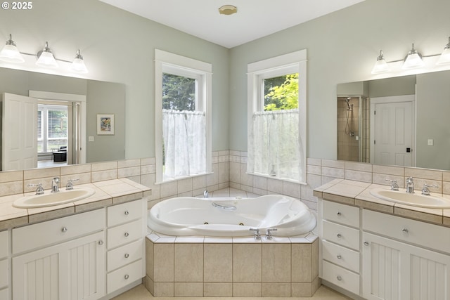 full bathroom featuring plenty of natural light, a tub with jets, two vanities, and a shower stall