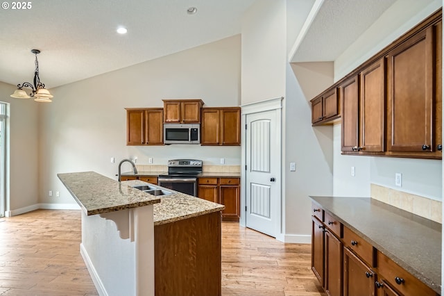 1080 Sage St, Silverton, OR 97381 - kitchen with stainless steel appliances, brown cabinets, light wood-style flooring, a chandelier, and high vaulted ceiling
