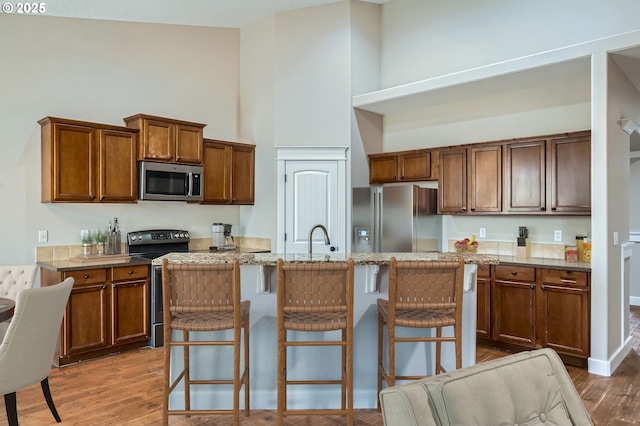 1080 Sage St, Silverton, OR 97381 - kitchen featuring stainless steel appliances, high vaulted ceiling, a kitchen island with sink, a kitchen bar, and wood finished floors