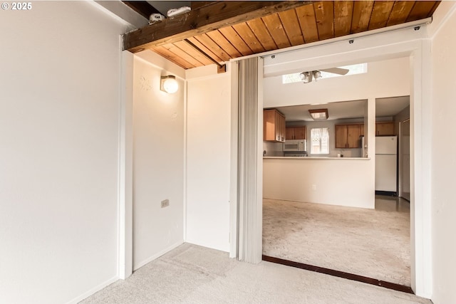 hallway featuring wooden ceiling, light colored carpet, and beamed ceiling