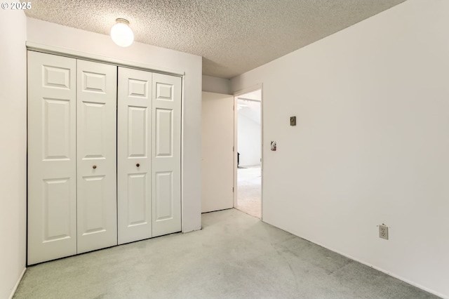 unfurnished bedroom with light carpet, a closet, and a textured ceiling