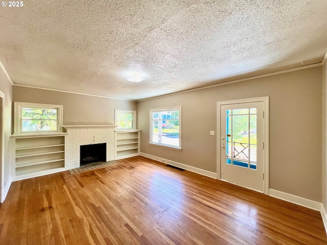 735 SE Spokane St, Portland, OR 97202 - unfurnished living room featuring a textured ceiling, wood finished floors, ornamental molding, baseboards, and a fireplace