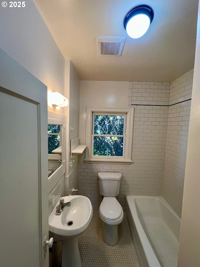 735 SE Spokane St, Portland, OR 97202 - full bathroom with tile patterned flooring, tile walls, toilet, a tub to relax in, and a sink